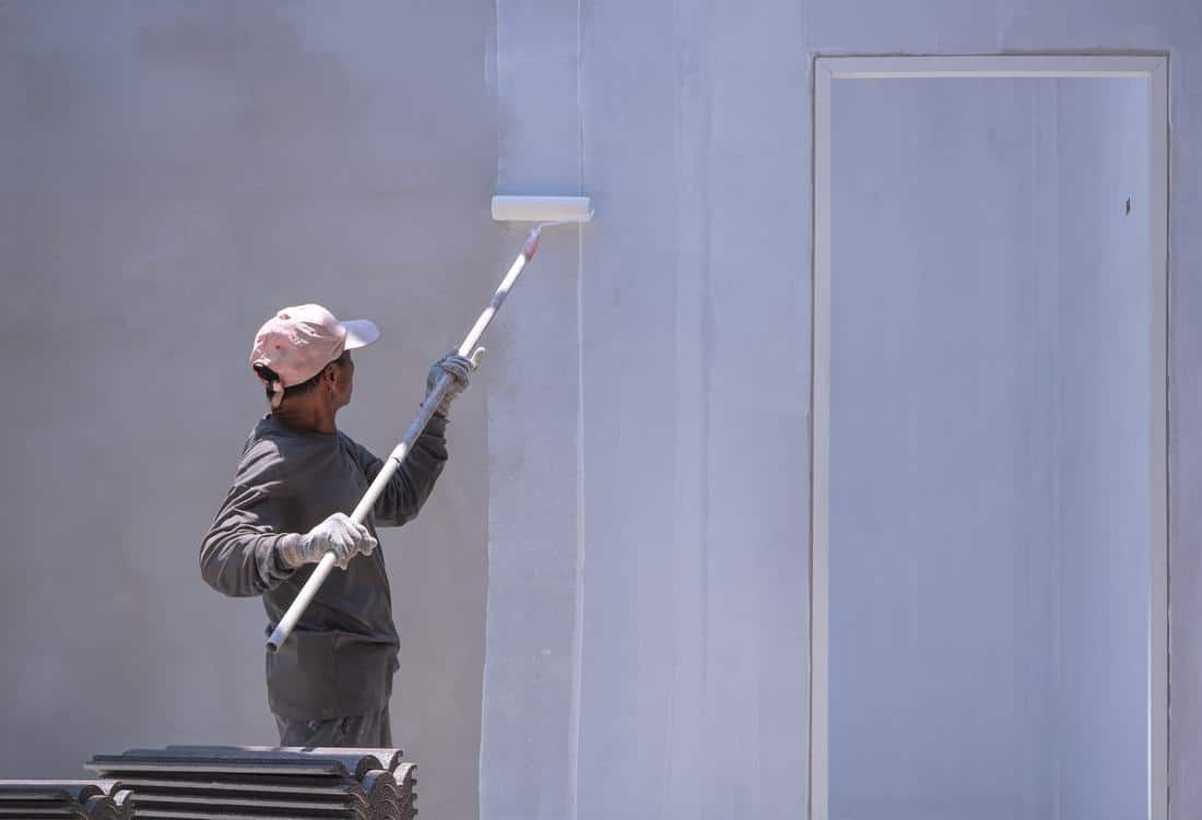 applying primer paint on house